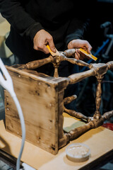 A man is a professional carpenter, a woodworker, applying putty and cement to a wooden chair in the workshop. Photography, handmade concept.