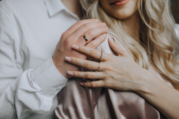 Hands with gold rings on the fingers of an embracing man and woman, bride and groom. Photography,...
