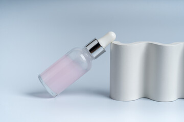 A dropper bottle for face care on a white concrete podium, presentation of product marketing