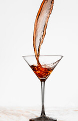 Liquore rosso che entra nel bicchiere da cocktail