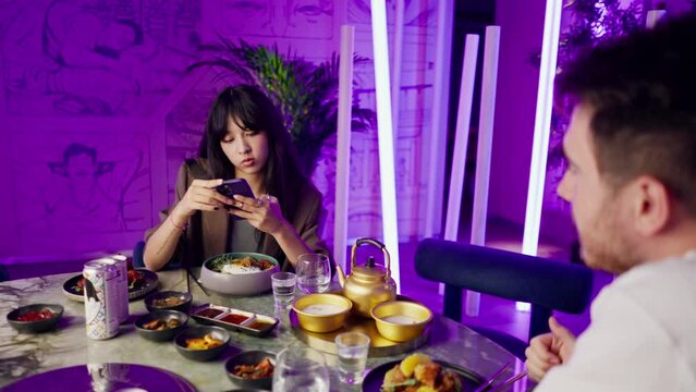 a young girl takes a picture on a smartphone of serving a drink in a teapot in a Korean restaurant