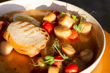 Fried Portuguese scallops in white wine sauce with lemon, tomatoes and toast. Seafood.