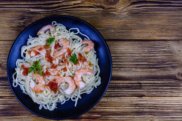 Italian pasta with shrimps and olives in a black plate. Top view