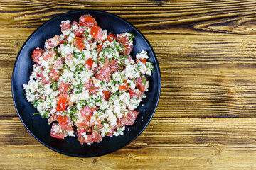 Salad with tomatoes, cottage cheese, dill and olive oil on a wooden table. Top view