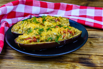 Plate with baked stuffed eggplants on a wooden table