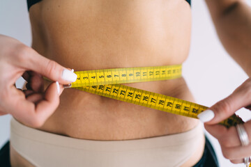 Slim woman measuring waist with tape