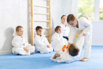 Fototapeta na wymiar Little children in white kimono training judo, jiu-jitsu indoors. Professional sports club for kids. Concept of martial arts, combat sport, sport education, childhood, hobby