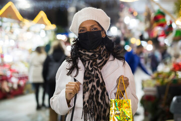 Portrait of a Latin American woman in a protective mask with a paper bag who came to an open-air Christmas fair during the ..pandemic