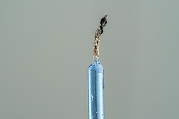 blue color wax candle with burnt and extinguished stir under grey background