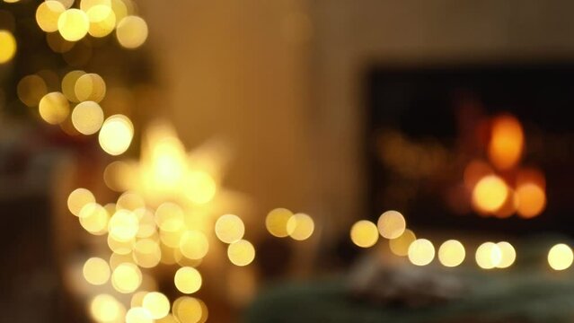 Cozy christmas eve. Stylish christmas tree with lights, illuminated star and burning fireplace in festive living room. Atmospheric winter hygge footage 