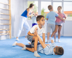 Kids practice grabbing their opponent's arms and taking them down in controlled manner.