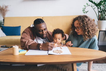 Multiethnic couple helping daughter with home work in living room