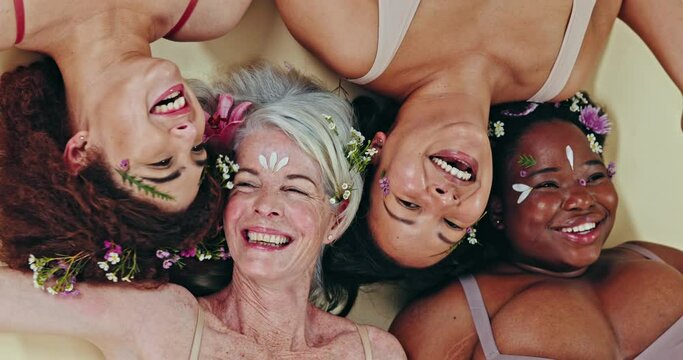 Diversity, face flowers and happy women laugh at funny sustainable beauty joke, creative glow or eco makeup on ground. Organic skincare group, above view and floral studio friends on green background