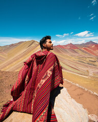 man in freedom at vinicunca rainbow montain in cusco peru with poncho
