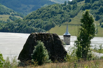 A massive boulder placed prominently amidst an expansive meadow, solitary and stoic, defying the...