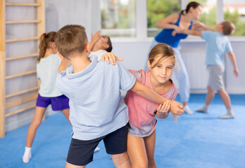 Boy and girl in gym perform basic elements of krav maga self-defense system. Preparation of...