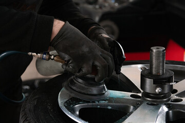 Detailer in a car service polishes a wheel rim with a pneumatic tool close up