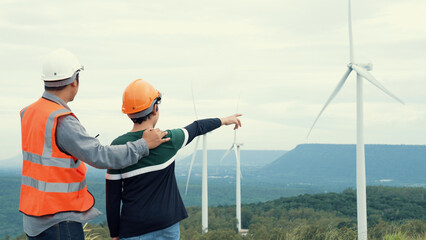 Engineer with his son on a wind farm atop a hill or mountain in the rural. Progressive ideal for...