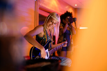 Obraz premium Female guitar player and singer in a recording studio, multicultural.