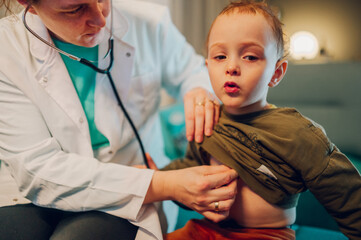 An ill boy is breathing while pediatrician is examining his lungs at home.