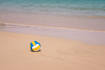 Fototapeta na wymiar Ball at sandy beach close to seashore line. Blue yellow white stripes. Close up photo
