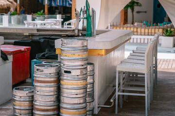 Metal beer barrels stand at a side of the summer open bar, close up photo