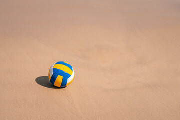 Obraz premium Ball at wet sandy beach. Blue yellow white stripes. Close up photo