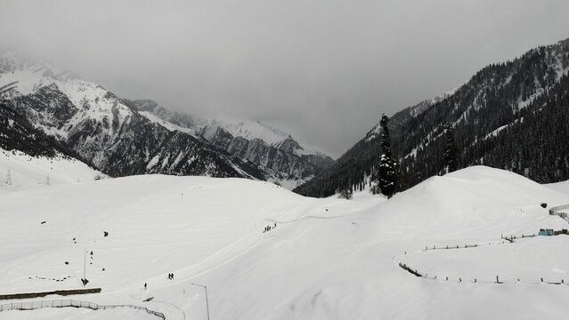 Aerial view of Sonamarg in Kashmir, India with forests and hills covered by snow and fog