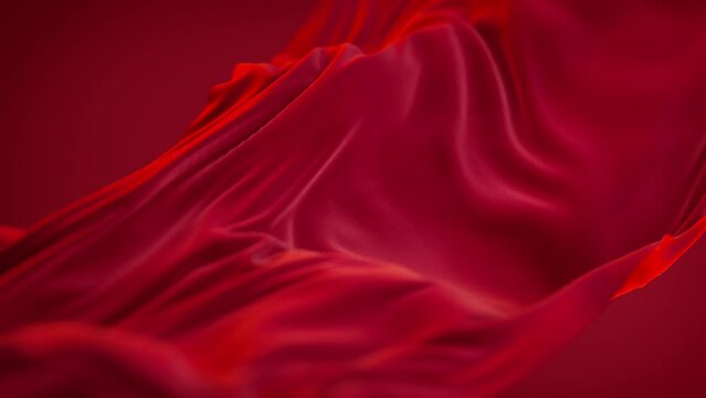 Red satin fabric floating slowly, close up on wavy luxury silk cloth flying in the air.