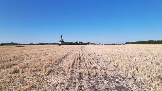 Agricultural field and Gai Monastery under the blue sky  in Arad, Romania