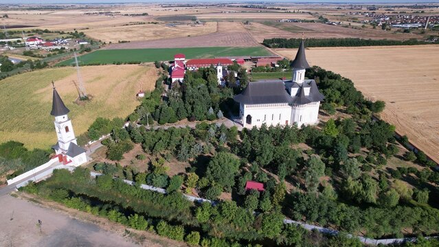 Aerial shot of Gai Monastery and green trees on a summer day in Arad, Romania