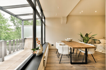 a dining table and chairs in a room with large windows looking out onto the trees that line the...