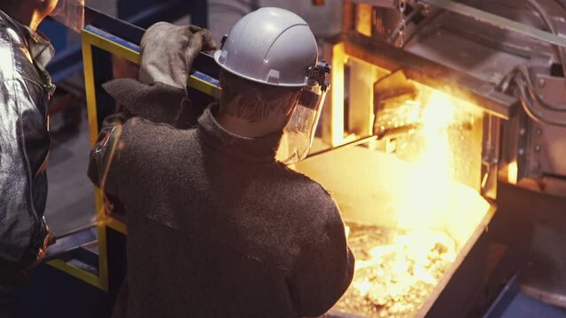 High amounts of molten steel are spilling out of the industrial furnace. Molten steel is extracted from the induction furnace at the factory. Molten steel flowing out of a burning furnace. Production.