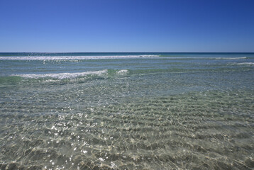 White sand and crystal clear water of Panama City Beach, Florida on cloudless sunny day.