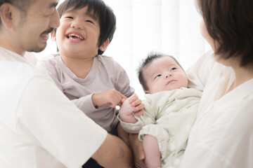 Fototapeta na wymiar 赤ちゃんを抱くパパとママ　仲良し4人家族みんなでいい笑顔のクローズアップ