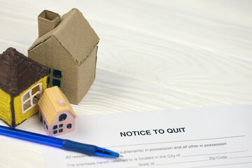 Notice to quit or eviction notice blank document paper ready to fill with small toy houses on table...