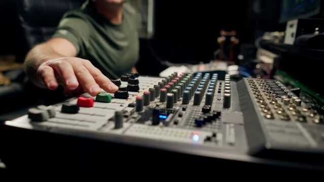 A close-up of a mixing console device used by a man working as professional sound engineer in a music studio