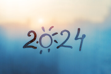 numbers 2024 of new year with shape of sun paint with finger on splashed by rain foggy glass on...