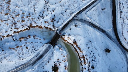 Large open stream running through a snow next to trees