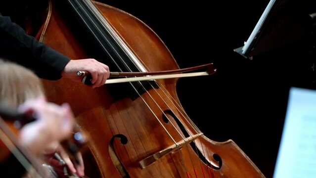 Violin and double bass close-up on a black background. Male and female hands in kadri. Static frame.