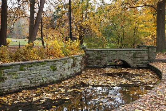 Beautiful view of a park with a river and stone bridge in autumn