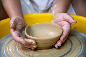 Obraz na płótnie Canvas Close up of females ceramics maker working with pottery wheel