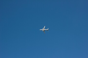 Fototapeta na wymiar White aircraft flying in the clear blue sky