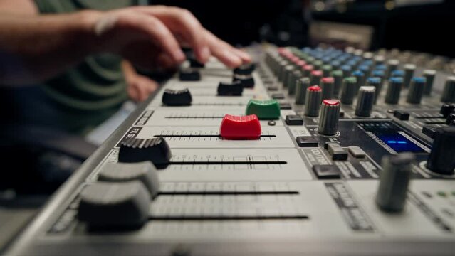 close-up shot of the male hand of a sound engineer switching settings on mixing console for recording a soundtrack