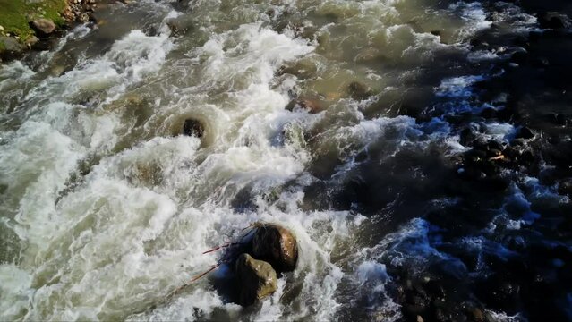 Closeup view of mountain river flowing through stones filmed at day time in slow motion. Scenery of rock creek with string current located in surroundings of Mingrelia in Georgia. Admiring nature