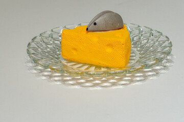 A single piece of cheesecake is shaped like a slice of a cheese wheel. There's a small grey...