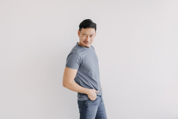 Happy asian man wears blue t-shirt and jeans winking at camera and smile