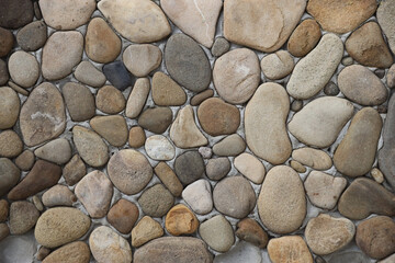 Yellow and brown round shaped pebble stone wall texture close up