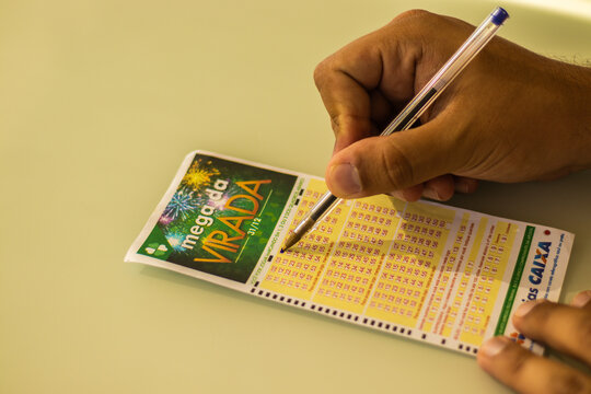 Mão masculina anotando os números em um volante da loteria brasileira mega sena da virada. Foto feita em São Paulo, SP, Brasil em 10 de Novembro de 2023