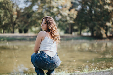 Cheerful girl enjoying a sunny day in a city park. Relaxing on a bridge surrounded by autumn...